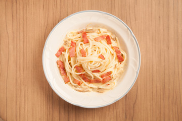 Spaghetti with bacon and cream sauce on plate.