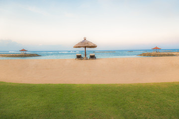 Palm trees on white sandy beach, two sunbed and parasol. View of nice tropical beach.