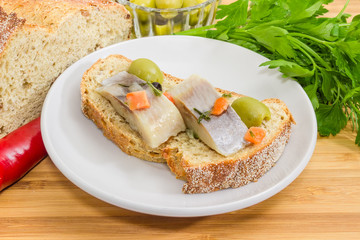 Open sandwich with pickled herring fillet among of some ingredients