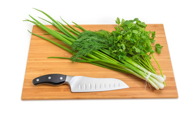 Fototapeta na wymiar Bunches of green onion, dill, parsley, knife on cutting board