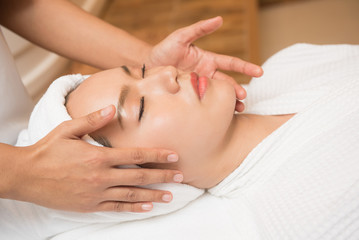 Face massage. Spa skin and body care. Close-up of young woman getting spa massage treatment at beauty spa salon. Facial beauty treatment.