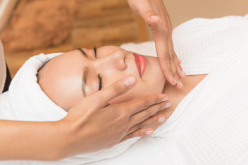 Fototapeta na wymiar Face massage. Spa skin and body care. Close-up of young woman getting spa massage treatment at beauty spa salon. Facial beauty treatment.