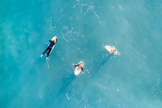 Three surfers in a calm ocean, top view