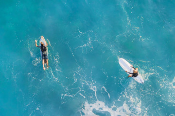 Two surfers in the ocean, top view - obrazy, fototapety, plakaty