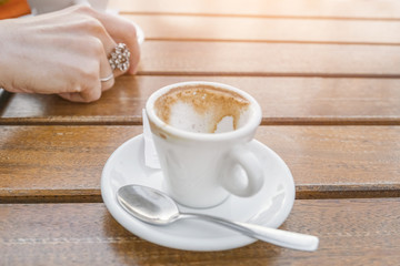 empty cup of coffee on a table near a woman's hand