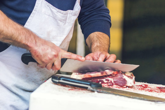 Butcher cuts a piece of meat on a table