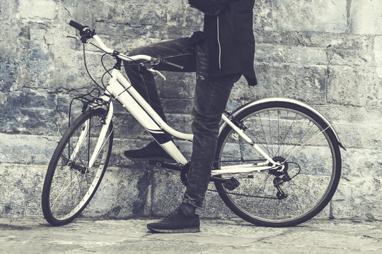 A man on a bicycle standing near a wall. Toned