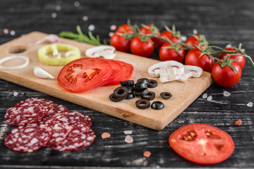 Preparation of the dough and vegetables to production of pizza. Ingredients for production of pizza on a wooden background