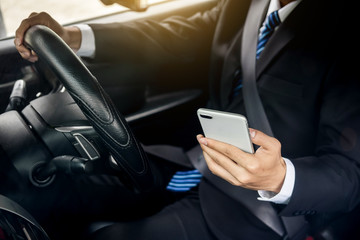 Attractive handsome young businessman using mobile smart phone in car