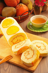 Orange swiss roll on the wooden cutting board     