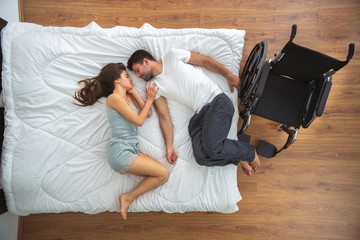 The woman and a disabled man laying on the bed. view from above