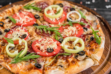 Vegetables, mushrooms and tomatoes pizza on a black wooden background. It can be used as a background