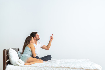 The happy couple on the bed gesturing on the white background