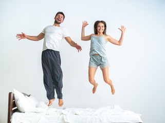 The couple jumping on the bed on the white background