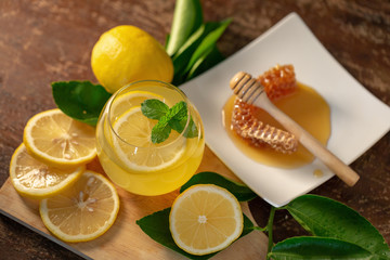 Lemon juice with honey on wooden table,  lemons and sage leaves