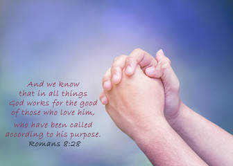 prayer hands of a man over blue sky background with bible verses from Romans 8:28 show Christian concept, God can make good things in believer in every situation, Christian background with copy space