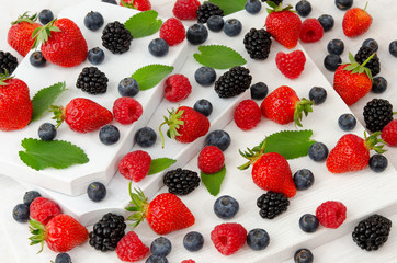 Verschiedene Beerensorten auf weißem Holzhintergrund