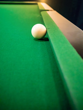 Cue ball on cushion on green snooker table.