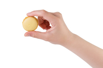young female hand holding yellow macaron isolated on white