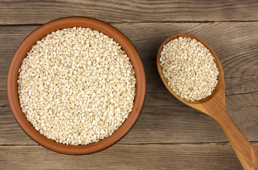 Sesame in a bowl on wooden background with a wooden spoon