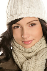Beautiful young brunette woman wearing a winter outfit with knitted woollen cap and scarf