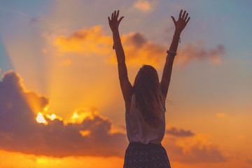 Girl with arms wide open enjoying sea / ocean scenery in sunset.