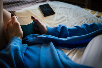 Woman with a cup of tea listening to music in bed
