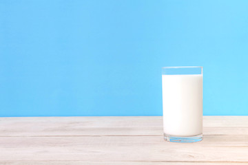 Glass of fresh milk isolated on table with blue background