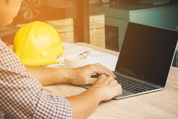 architect man working with laptop and blueprints : sketching a construction project ,engineer inspection in workplace for architectural plan, selective focus, Business concept vintage color.