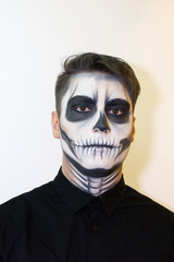 man in make-up Halloween. drawing a vampire, skeleton on his face. Close-up photo.