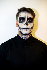 man in make-up Halloween. drawing a vampire, skeleton on his face. Close-up photo.