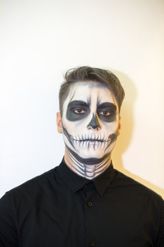 man in make-up Halloween. drawing a vampire, skeleton on his face. Close-up photo.