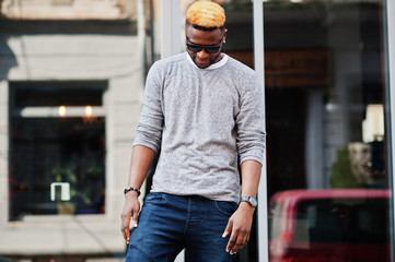Stylish african american boy on gray sweater and black sunglasses posed at street. Fashionable black guy.