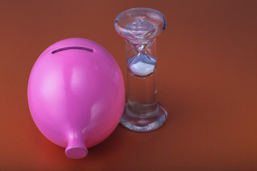 piggy Bank with hourglass close-up. The concept of saving and accumulation money