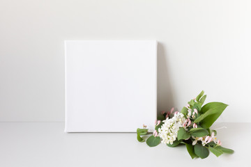 Mock up poster on gray background. White square canvas and romantic bouquet of flowers.