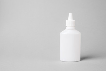 Spray for the nose in a white plastic bottle on a gray background. Aerosol from the common cold or allergy. mock-up