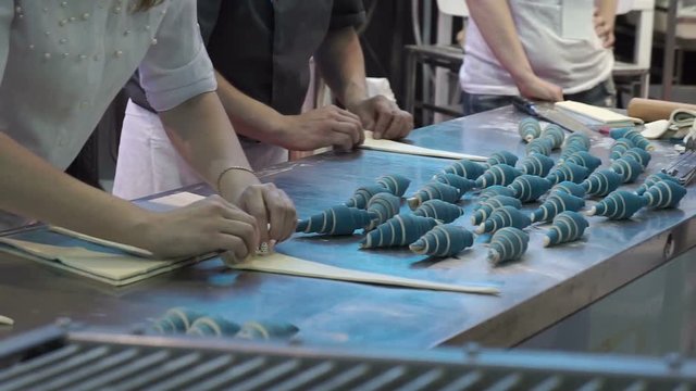 A bakers turns beautiful croissants before baking.