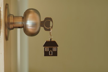 Home key with house keychain in keyhole, property concept