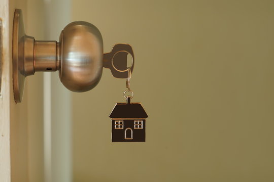 Home key with house keychain in keyhole, property concept