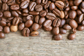 Roasted coffee beans on rustic wooden background. Food ingredients, top view, space for text