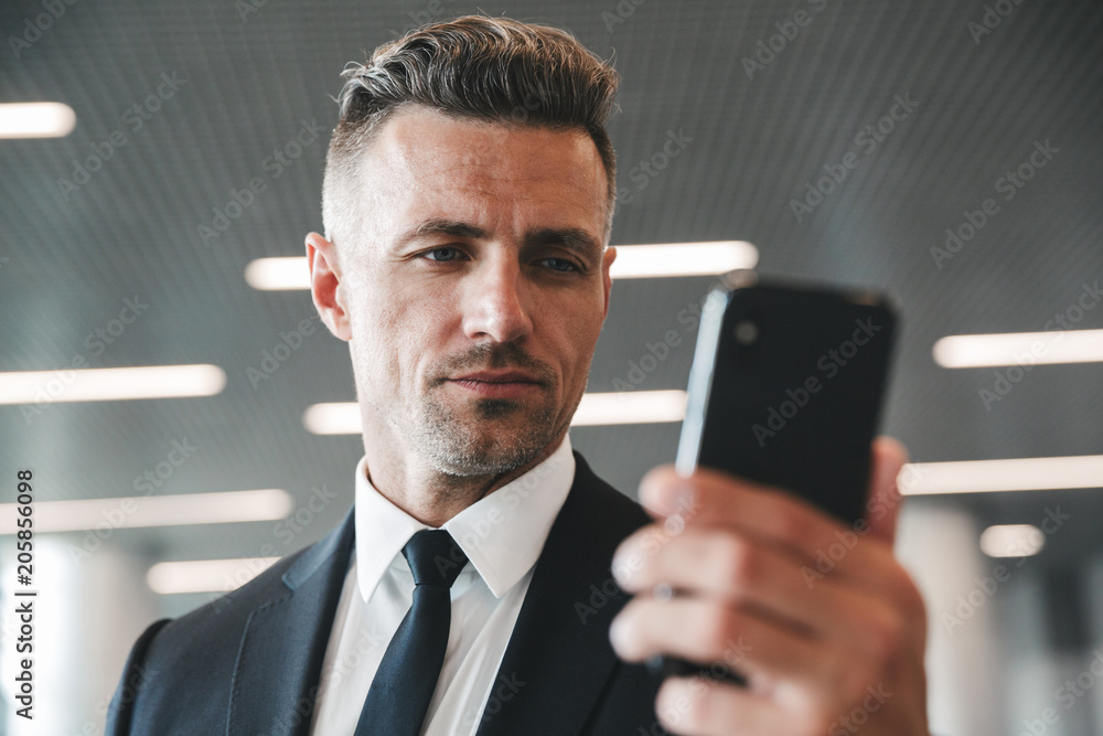 Wall mural concentrated mature businessman looking at mobile phone