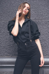 Beautiful girl in black clothes oversize with suspenders. Dark background. Toned image.
