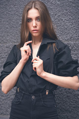 Beautiful girl in black clothes oversize with suspenders. Dark background. Toned image.