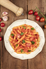 Overhead photo of penne pasta with tomato sauce and ingredients with copy space