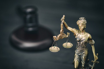 Scales of Justice, Judge Gavel, Justitia, Lady Justice on a black wooden background.