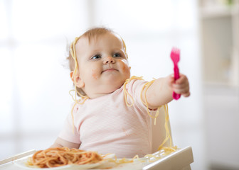 Little baby toddler eating her pasta and making a mess