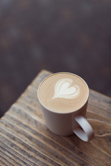 Cup of cappuccino coffee with heart shape latte art on the wood table