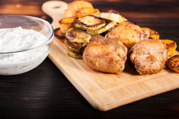 Dinner made of fried chicken and grilled vegetables and a glass bowl of sour cream souce