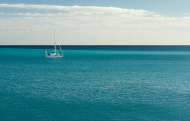 Blue Atlantic Ocean with white yacht on the horizon