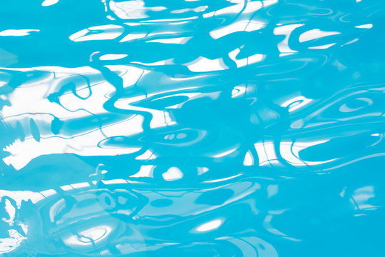 Blue pool water with sun reflections. Abstract blurred pattern.